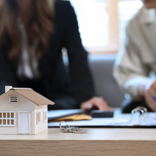 House model on wooden table and financial adviser consulting co House model on wooden table and financial adviser consulting contract mortgage loan with elderly man in background.